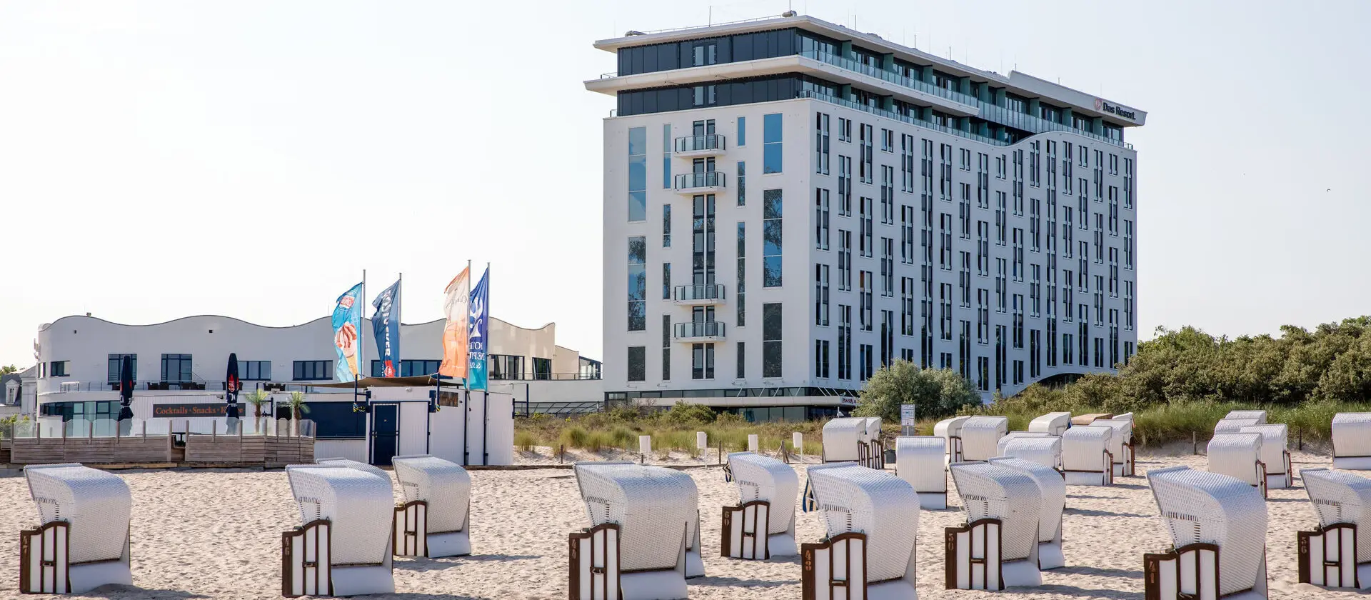 Das aja Warnemünde direkt am Strand mit Strandkörben im Vordergrund.
