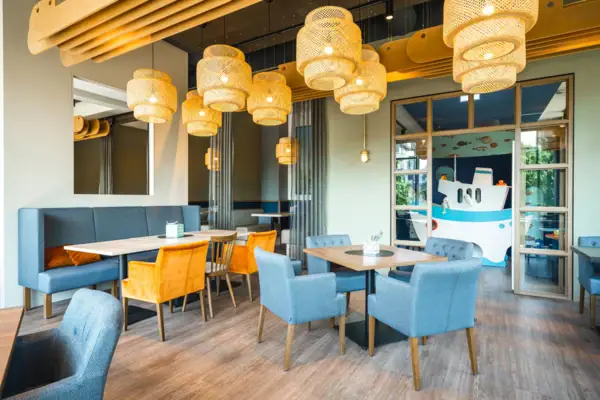 Restaurant und Bar im aja Warnemünde Ein Raum mit einem Tisch und Stühlen im Hintergrund ist das Spielzimmer zu sehen.