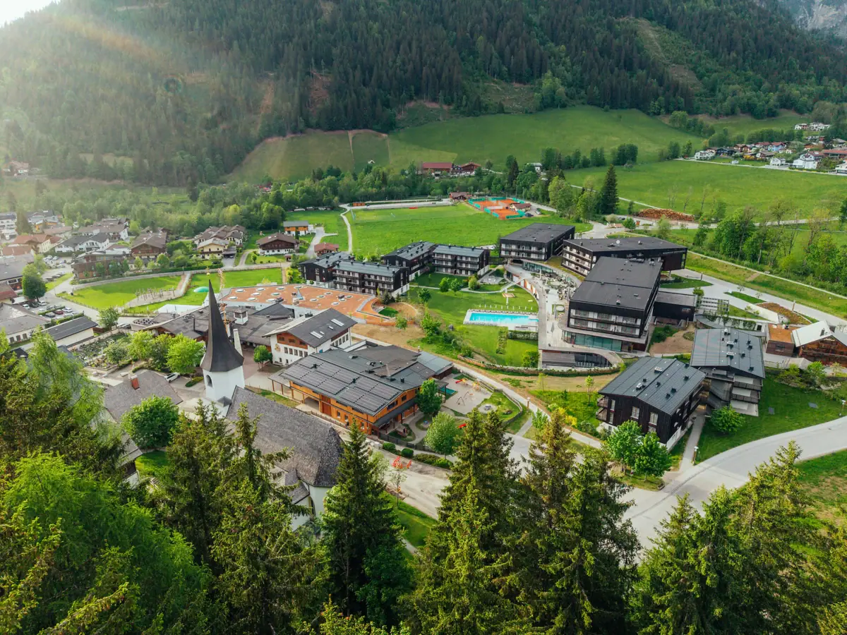Bergresort Werfenweng Eine Stadt mit vielen Gebäuden und einem Pool in der Mitte eines Tals.