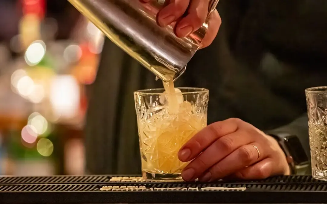 Drinks Barkeeper gießt einen Cocktail in ein Glas.