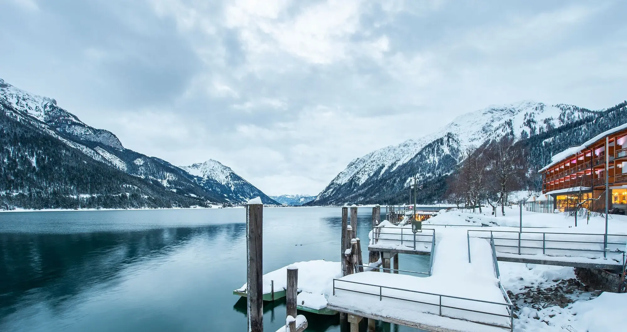 Achensee im Winter Schneebedeckter Steg an einem See mit Bergen im Hintergrund.