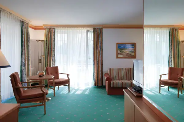 Suite Wohnbereich Ein Zimmer mit einem Fernseher und Stühlen.
