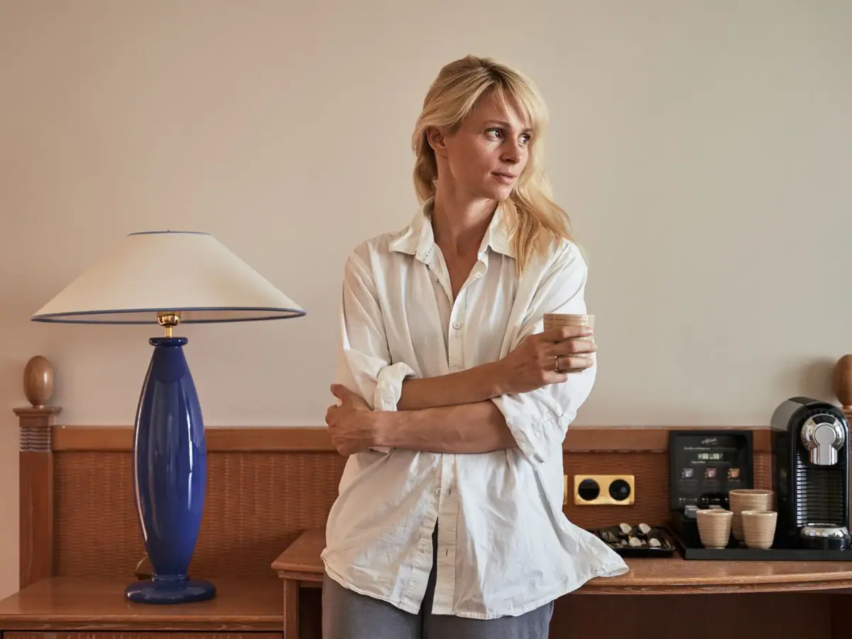 Zimmer Eine Frau steht vor einem Tisch mit einer Lampe und einer Kaffeetasse.