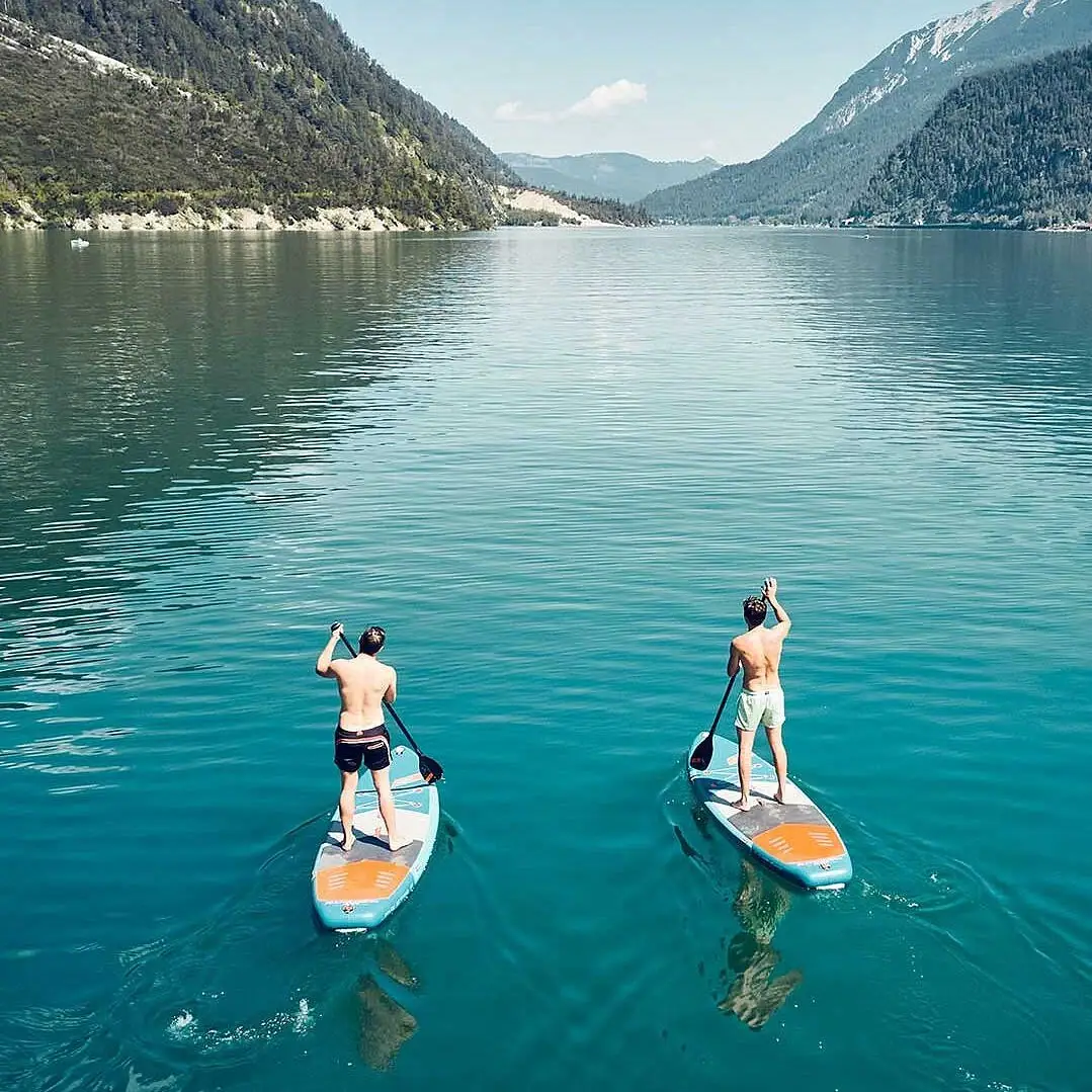 SUP auf dem Achensee Zwei Männer auf Paddleboards auf einem See.