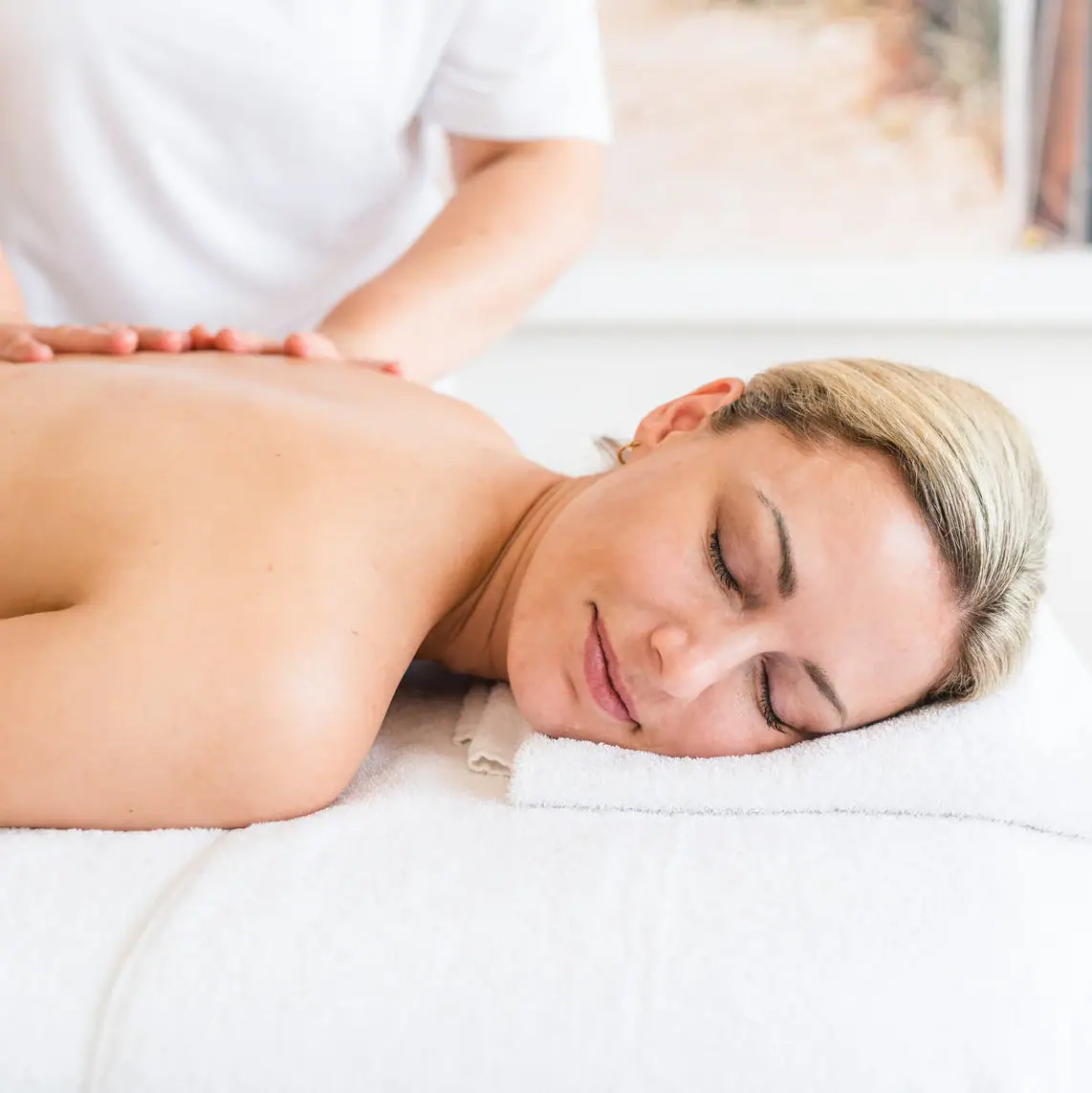 Anwendungen im aja Warnemünde Eine Frau liegt auf einem Massagetisch.