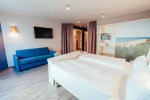 Handicap Zimmer Ein Zimmer mit zwei Betten und einem blauen Sofa.