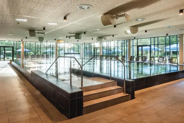 aja SPA in Bad Saarow Großes Hallenbad mit Treppe und Geländer.