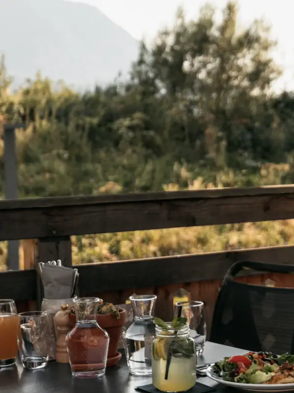 Mittagessen Ein Tisch mit Essen, umgeben von Stühlen und einem Sonnenschirm.