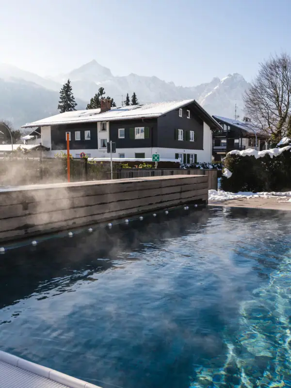 Außenpool im Schnee Ein dampfender Außenpool mit Bäumen im Hintergrund.