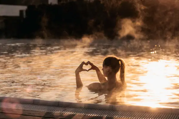 Außenpool im Winter Eine Frau im Pool mit den Händen im Wasser.