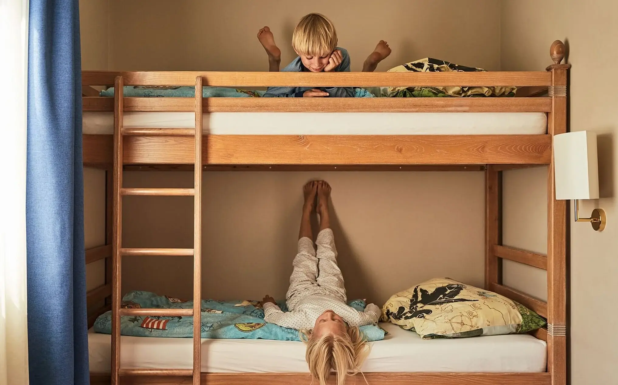 Familienzimmer aja Bansin Ein Junge liegt oben auf einem Etagenbett neben einer Leiter.