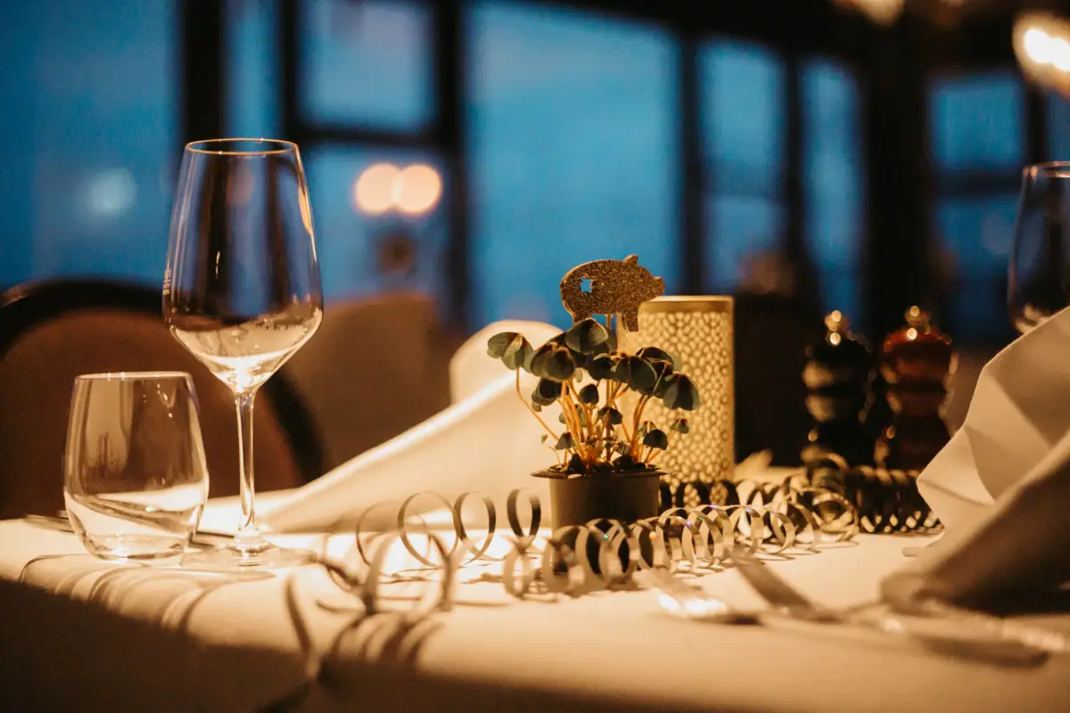 Silvester im aja Grömitz Ein Tisch mit einem Weinglas und einer Pflanze darauf.