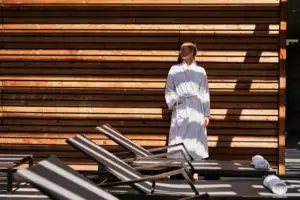 Liegenbereich Eine Frau in einem weißen Bademantel steht vor einer Holzwand.