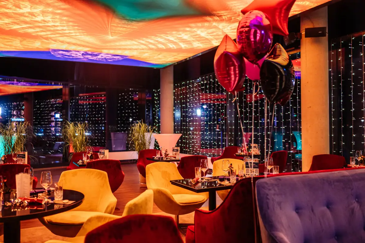 Silvester im aja Travemünde Ein Raum mit Tischen, Stühlen und Luftballons.