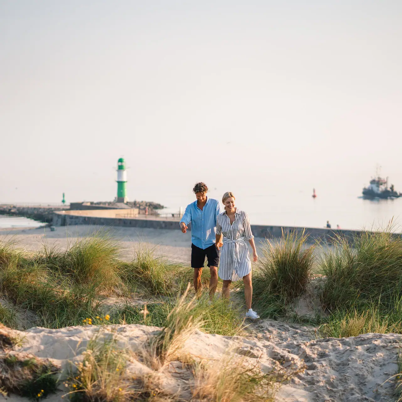 Erlebnisse im aja Warnemünde Ein Mann und eine Frau gehen am Strand entlang.