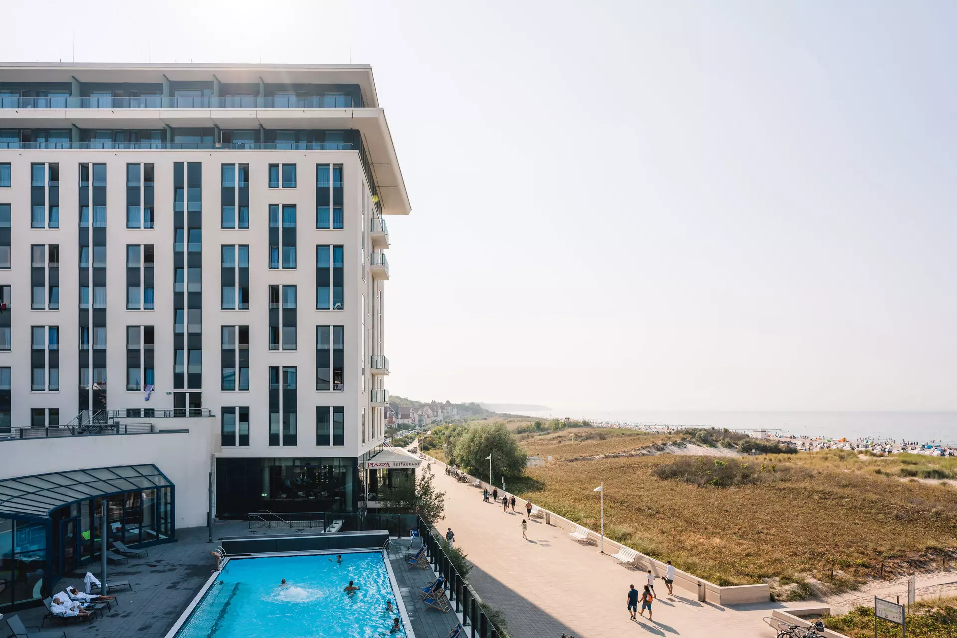 aja Warnemünde Gebäude mit Pool und vorbeigehenden Menschen
