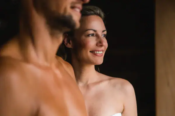 BIO-Sauna im aja Warnemünde Ein Mann und eine Frau lächeln und stehen in einer Sauna.