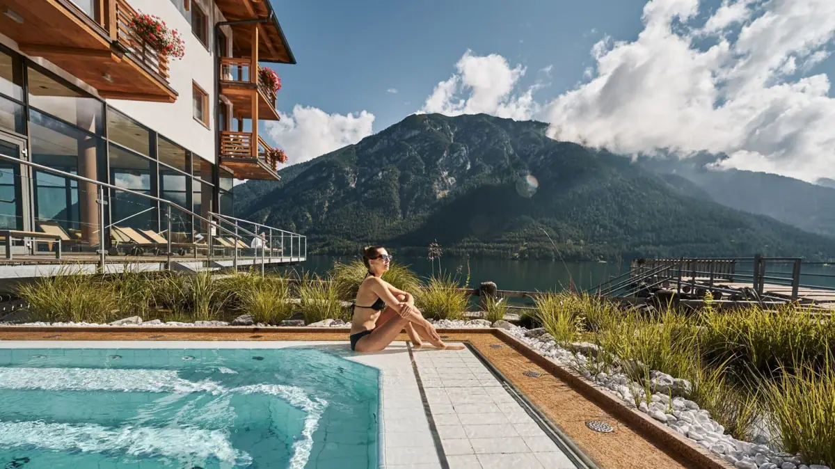 Whirlpool mit Seeblick Eine Frau sitzt an einem Pool mit einem Berg im Hintergrund.
