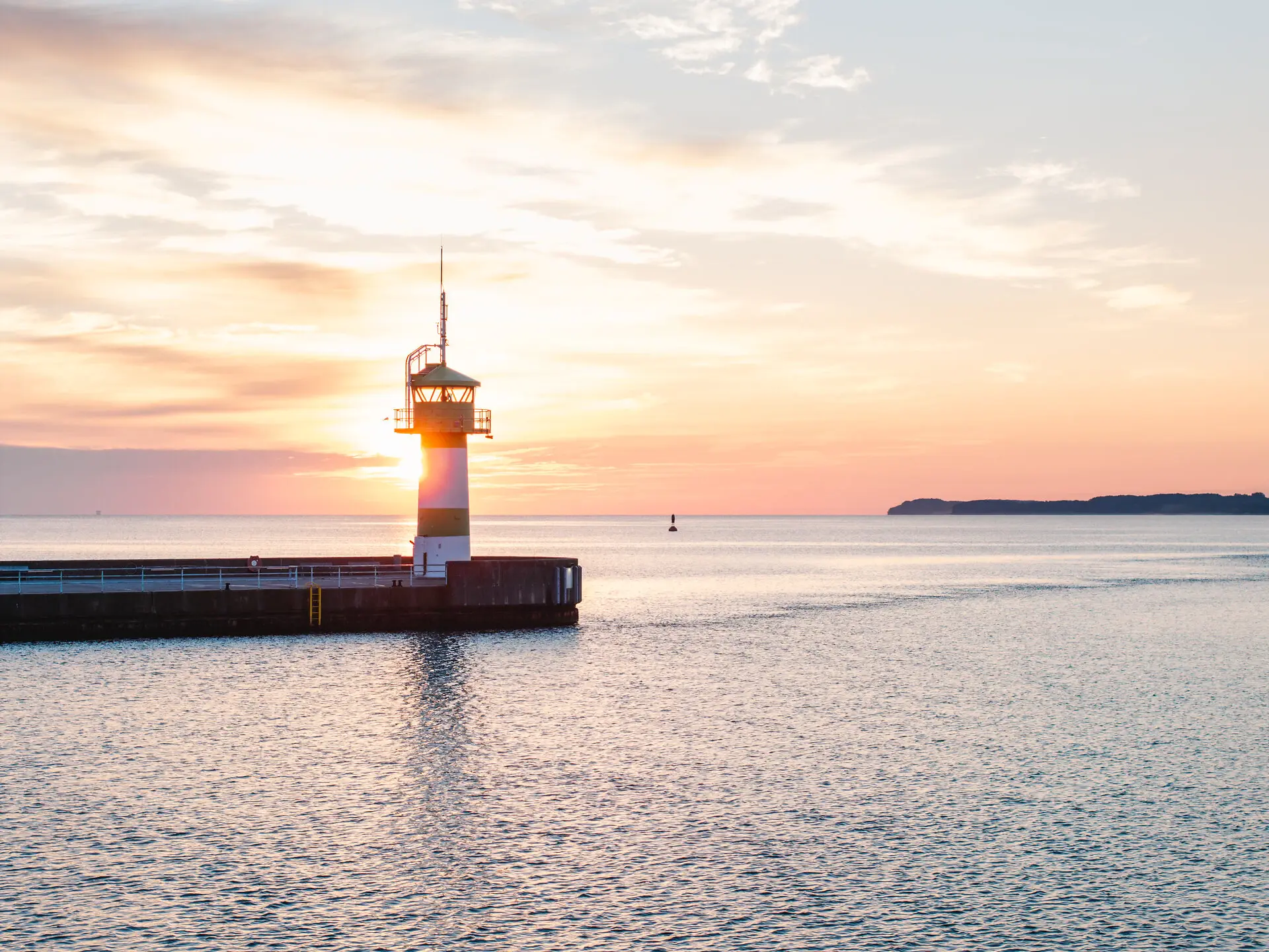 Travemünde Ein Leuchtturm auf einem Steg inmitten des Ozeans.