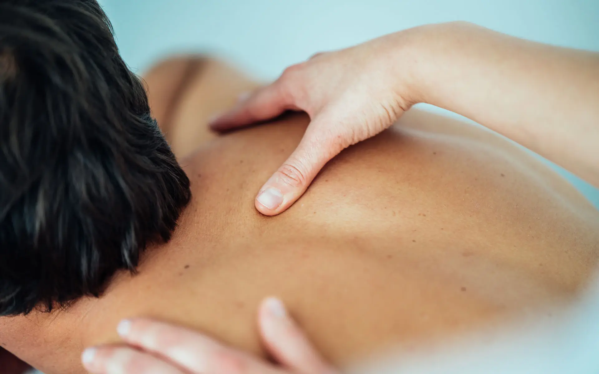 Ein Mann liegt auf einer Massageliege und bekommt seinen Rücken massiert.