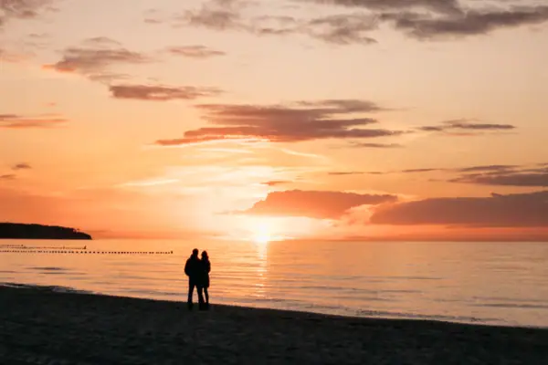 Sonnenuntergang Ein Paar steht am Strand bei Sonnenuntergang.