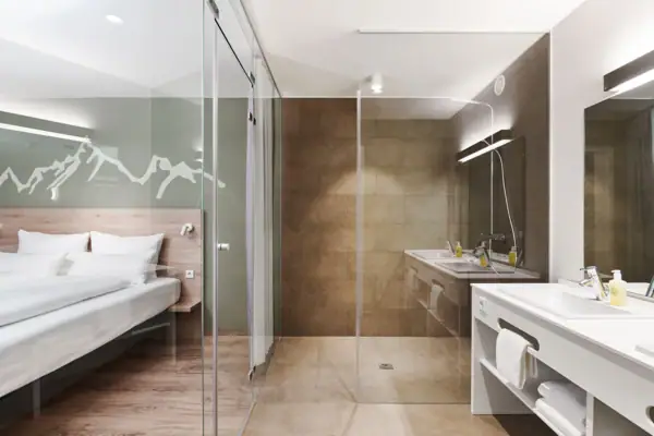 Suite Badezimmer Ein Badezimmer mit einer Glasdusche und einem Bett.