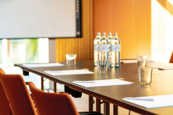 Tagungsraum Ein Tisch mit Papieren und Brillen darauf.