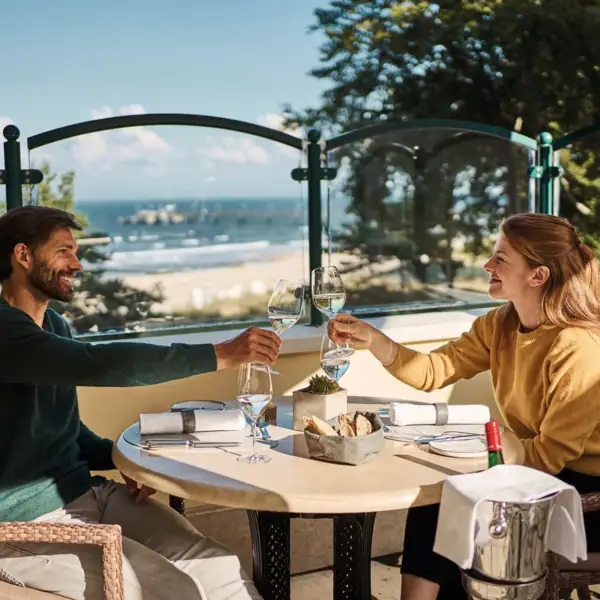 Ein Mann und eine Frau sitzen an einem Tisch mit Weingläsern.