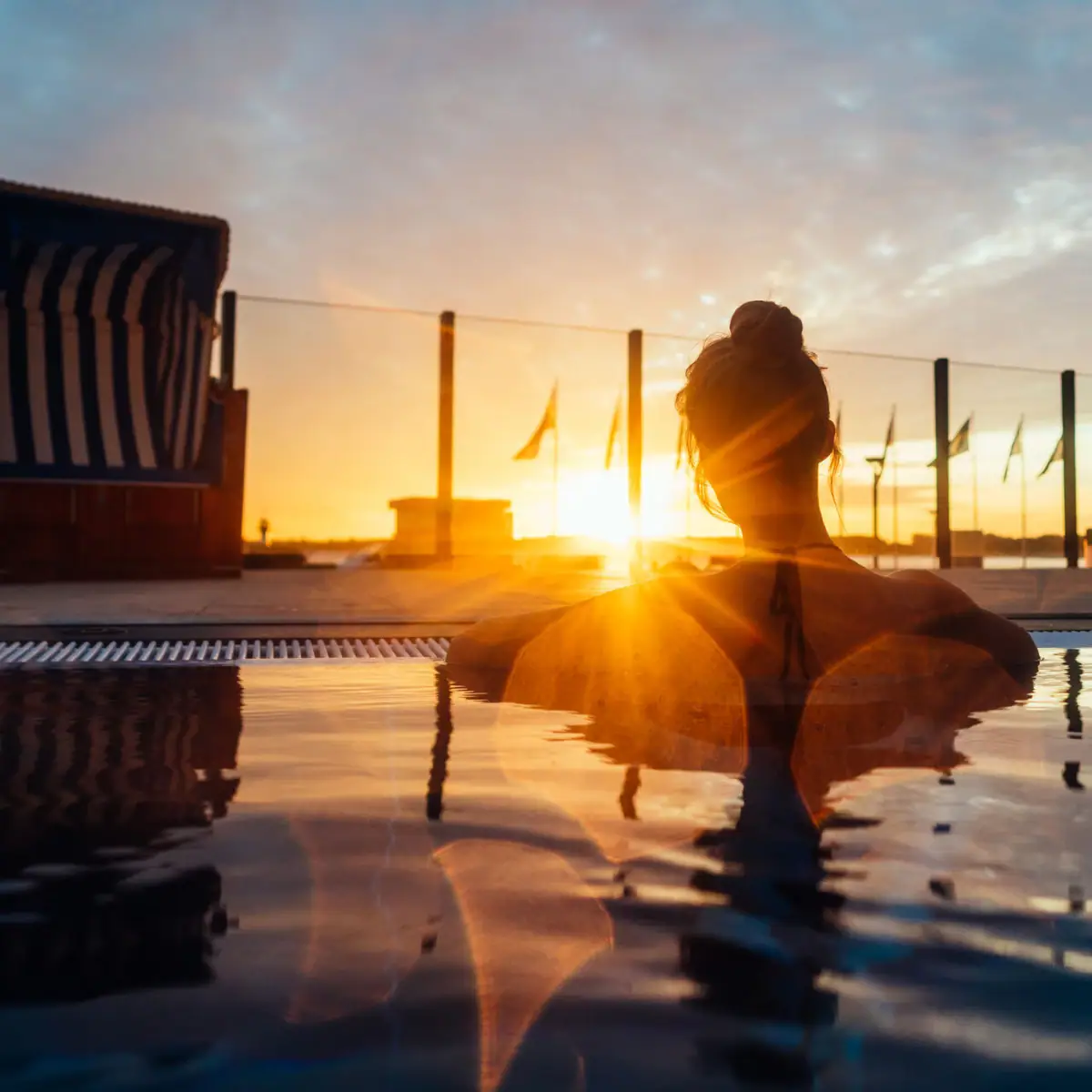 Frau im Außenpool Eine Frau entspannt in einem Pool mit Sonnenuntergang im Hintergrund.