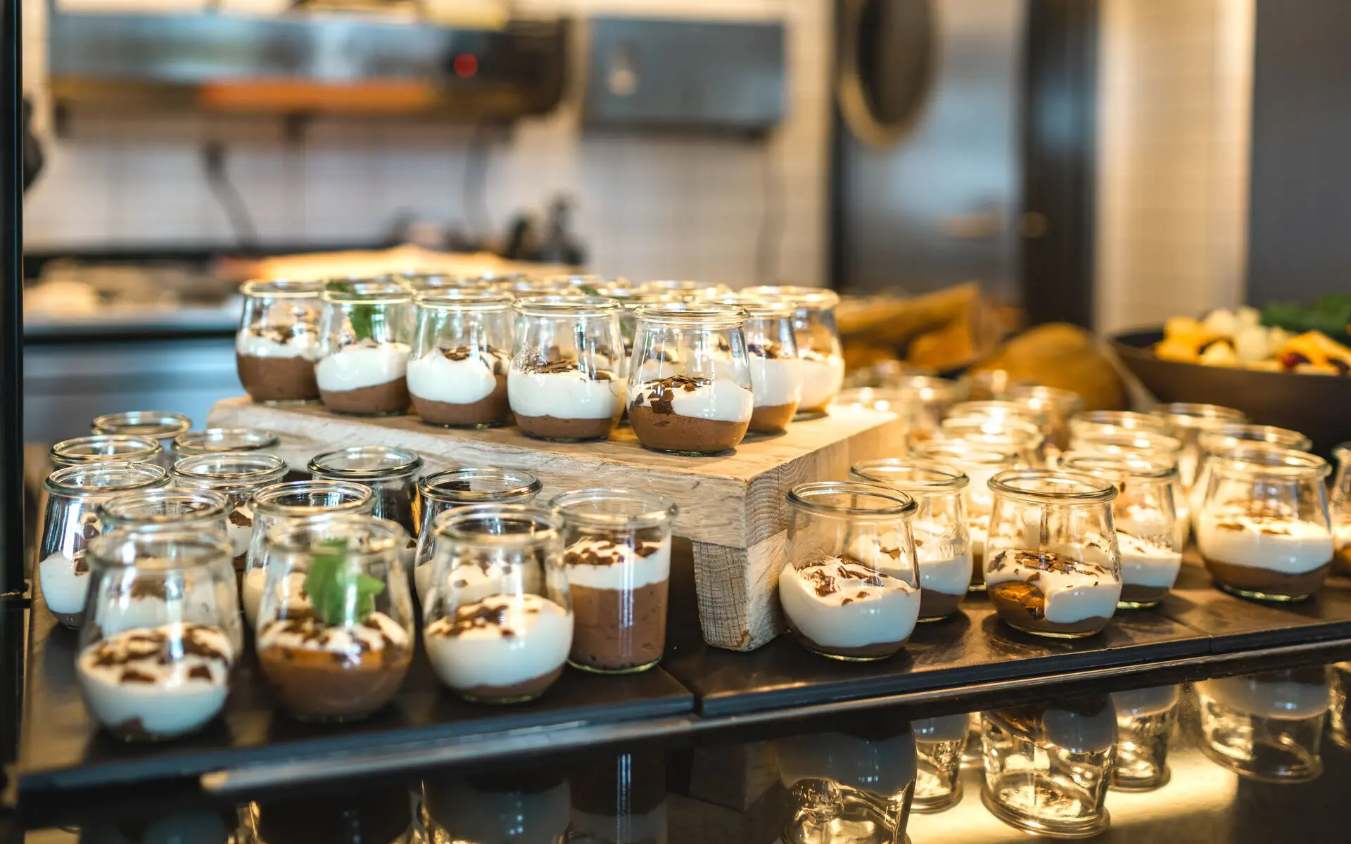 Dessert im aja Bad Saarow Ein Buffetbereich mit vielen Dessertgläsern, gefüllt mit heller und schokoladieger Creme.