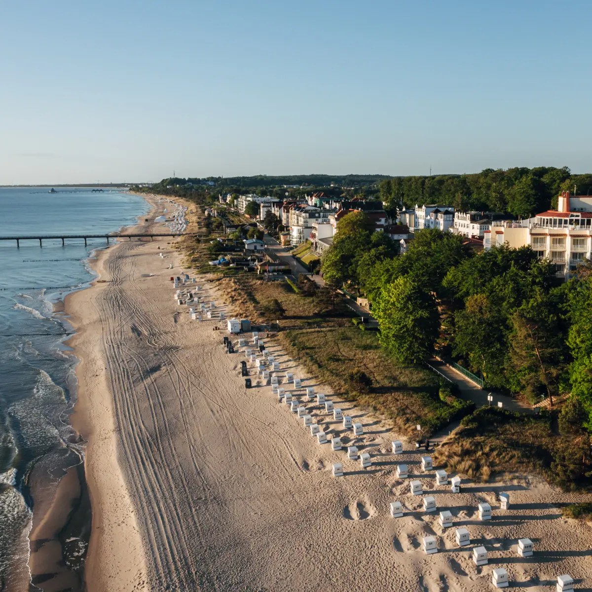 aja Strandhotel Bansin Strand mit Gebäuden und Bäumen im Vordergrund.