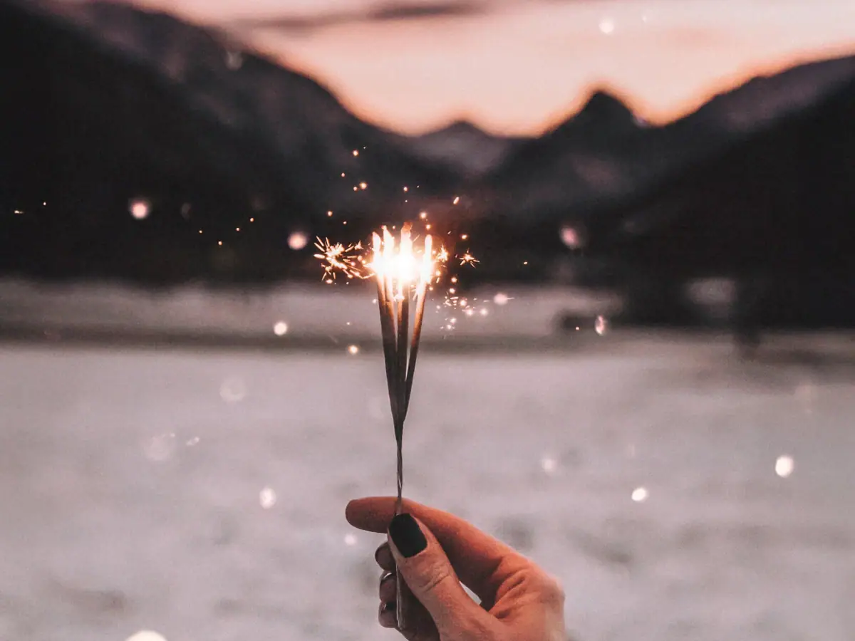 Wunderkerze Hand hält eine Wunderkerze vor einem Himmel im Hintergrund die Berge