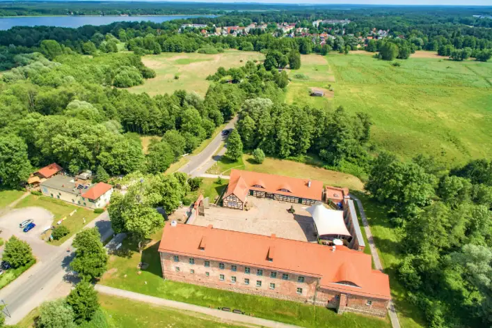 Burg Storkow besuchen Ein großes Gebäude umgeben von Bäumen.