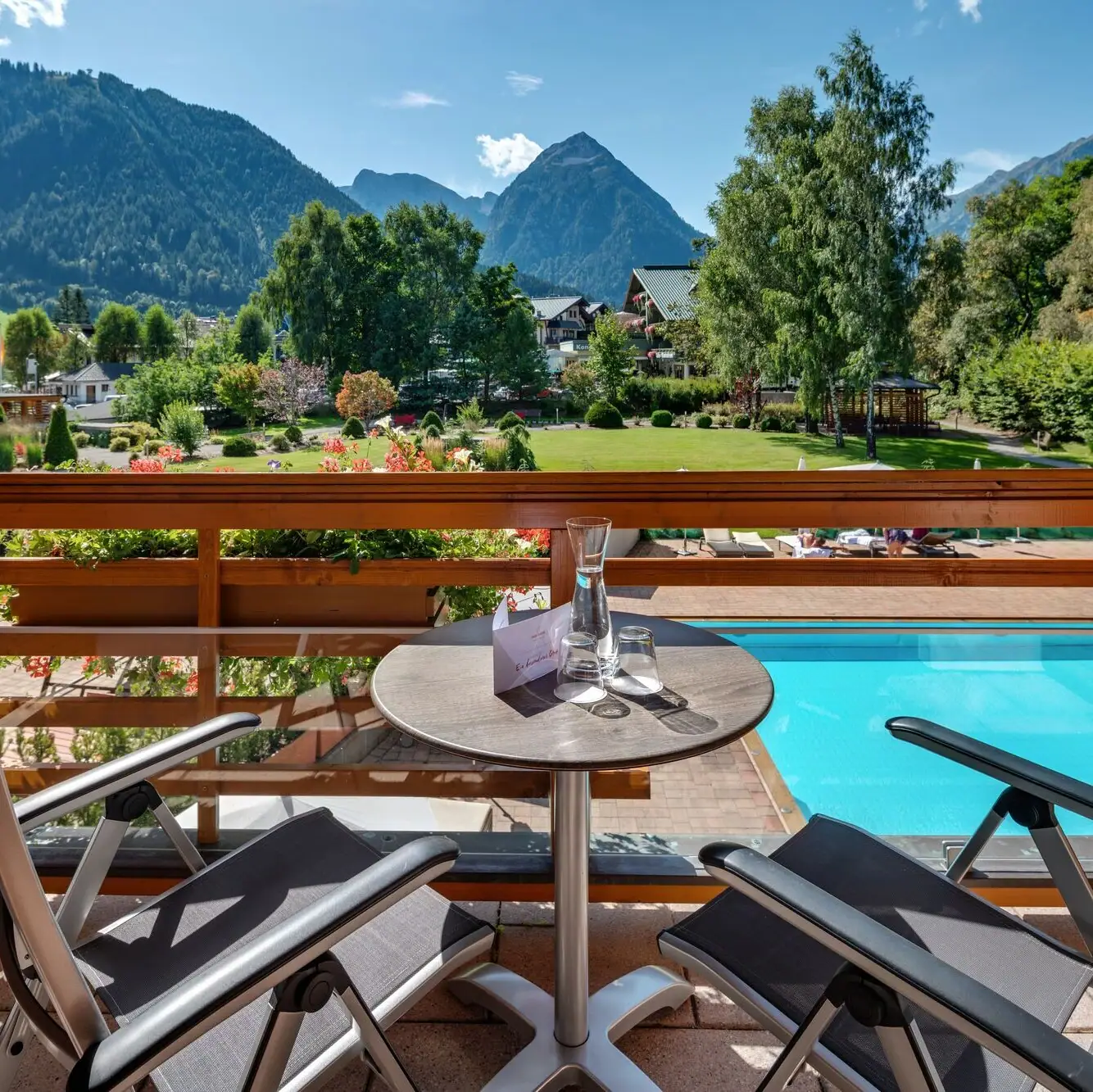 Zimmerausblick Ein Tisch und Stühle auf einem Balkon mit Blick auf einen Pool.