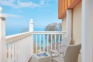 Juniorsuite seeseitig mit Balkon Ein weißer Stuhl und Tisch auf einem Balkon mit Blick auf das Meer.