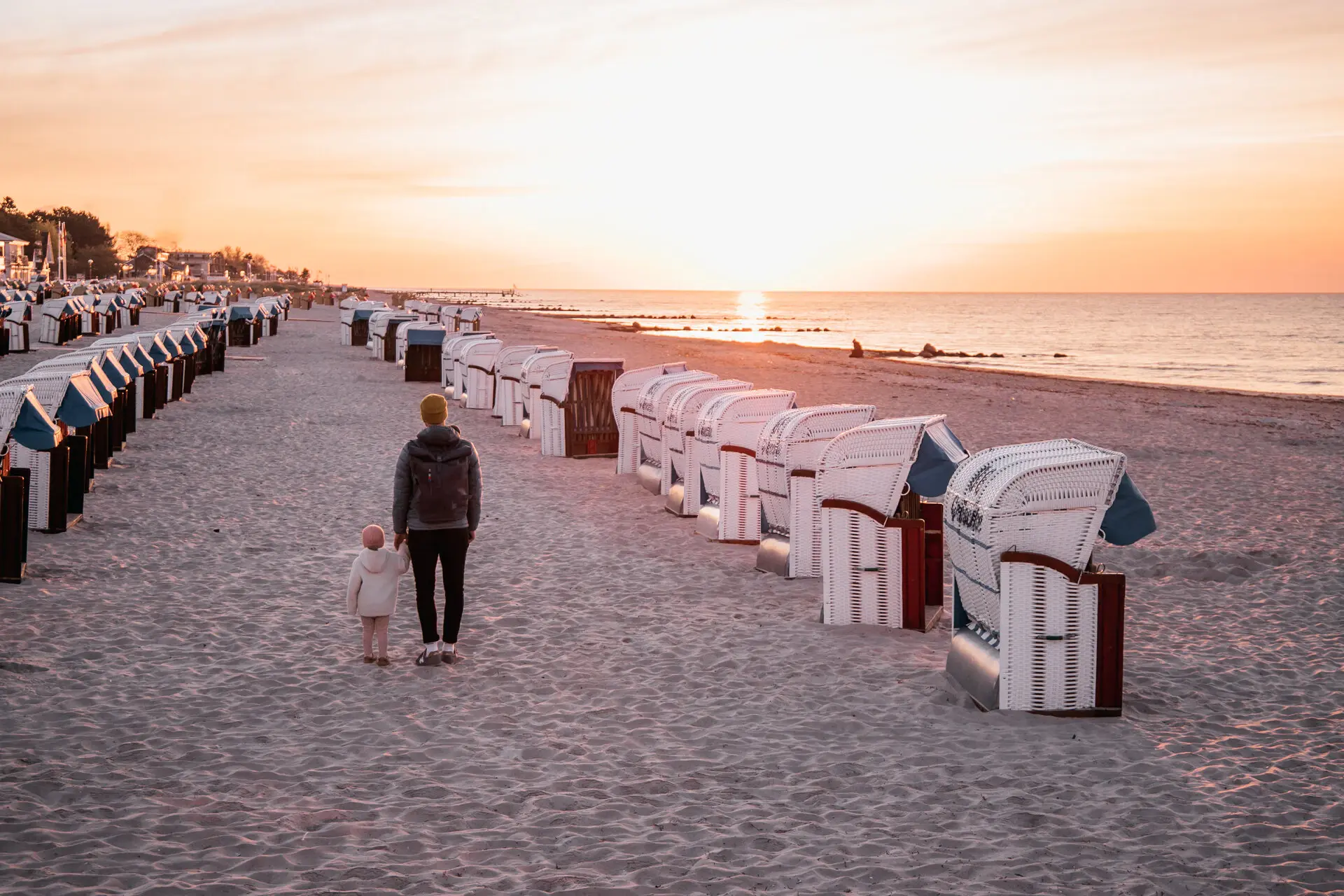 Strand Grömitz Eine Frau und ein Kind spazieren am Strand wischen aufgereihten Strandkörben entlang