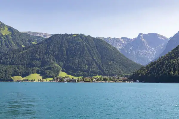 Achensee Ein Gewässer mit Bergen im Hintergrund.