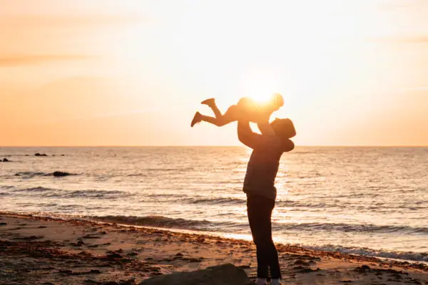Familie am Strand Eine Frau hält ein Baby am Strand.