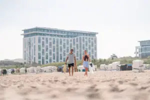 aja Warnemünde Ein Mann und eine Frau spazieren am Strand.
