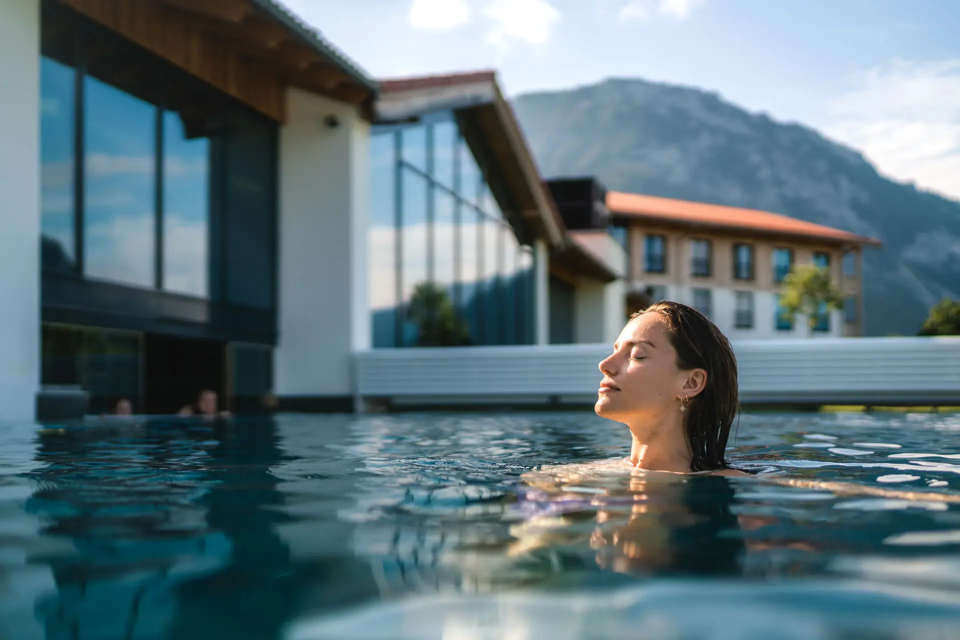 Außenpool aja Ruhpolding Eine Frau mit geschlossenen Augen in einem Schwimmbecken.