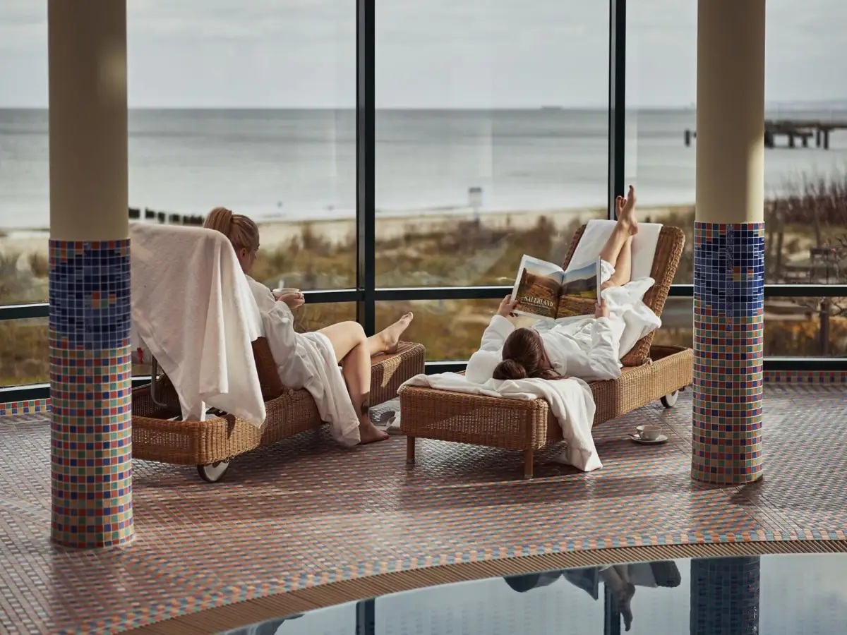 Eine Gruppe von Frauen in weißen Roben liegt auf Stühlen am Pool.