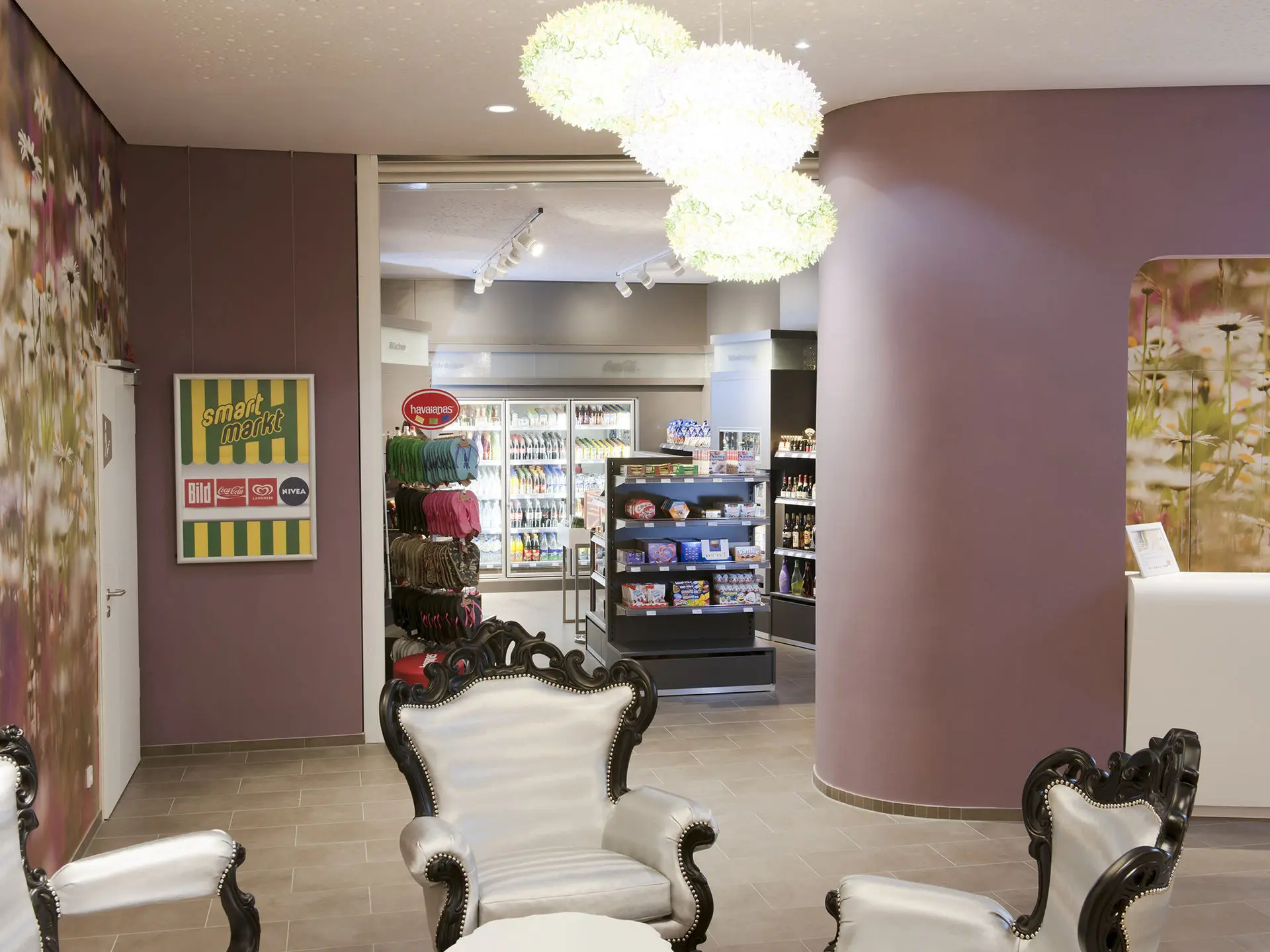 Ein Empfangsbereich mit weißen Sesseln und einem kleinen Shop im Hintergrund.